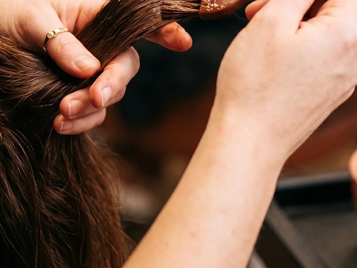Stylist's hands applying hair color with a tinting brush